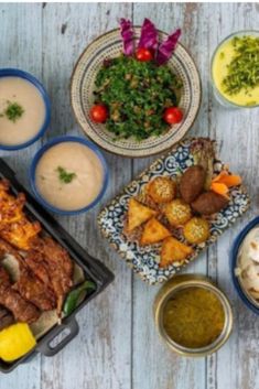 a table topped with plates and bowls filled with different types of food next to dipping sauces