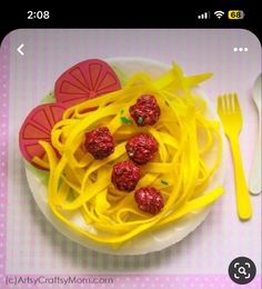 a white plate topped with pasta and veggies on top of a pink table