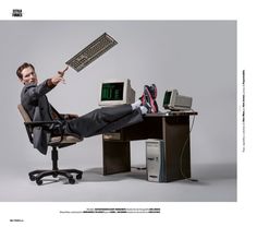 a man sitting in an office chair holding up a computer