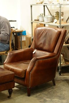 a man sitting in a leather chair next to a foot stool