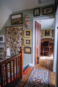 the hallway is decorated with many framed pictures and paintings on the wall, along with a rug