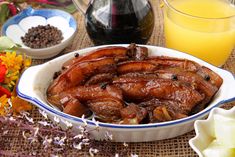 a bowl filled with meat next to some flowers and orange juice in a glass pitcher