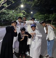 a group of young men standing on the side of a road with their hands in the air