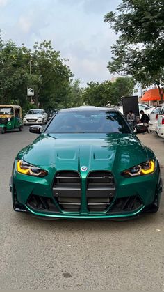 a green sports car is parked on the side of the road in front of other cars