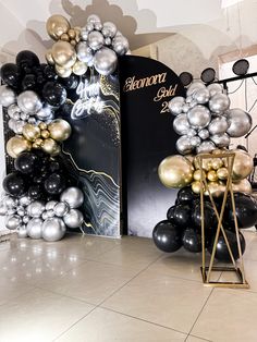 an entrance decorated with black, silver and gold balloons