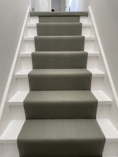 a set of stairs with carpeted treads in a home entryway, leading up to the second floor