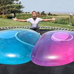 a man on a trampoline with two giant balls in front of him and another one behind him