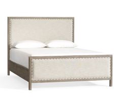 an image of a bed with white linens and studded trimmings on the headboard