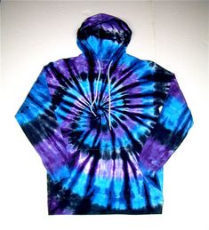 a blue and purple tie - dyed hoodie is hanging on the wall in front of a white wall