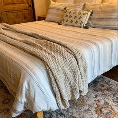 a bed with two pillows on top of it and a blanket over the headboard