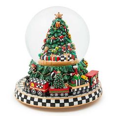 a snow globe with a train and christmas tree in the center, on top of a black and white checkered plate