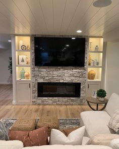 a living room with white couches and a flat screen tv mounted on the wall