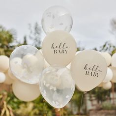 balloons with the words hello baby written on them are in front of some trees and bushes