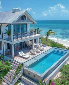 an aerial view of a house with a swimming pool in the foreground and ocean in the background