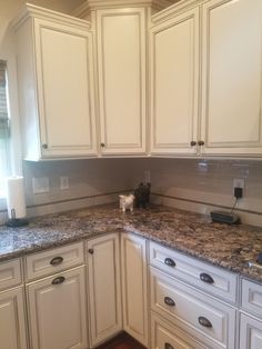 a kitchen with white cabinets and granite counter tops