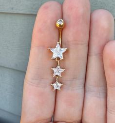 a person is holding a gold and white star belly ring with five stars on it