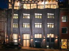 a car driving past a tall brick building at night with lights shining on the windows