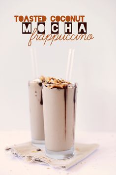 two glasses filled with chocolate milkshakes sitting on top of a white tablecloth