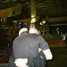 two people hugging each other in front of a tv screen at an airport or building