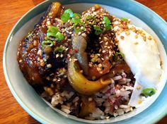 a bowl filled with rice, meat and veggies on top of a wooden table