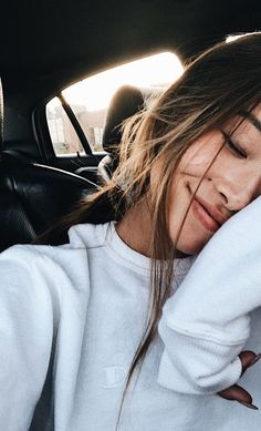 a woman sitting in the back seat of a car with her head resting on her hand