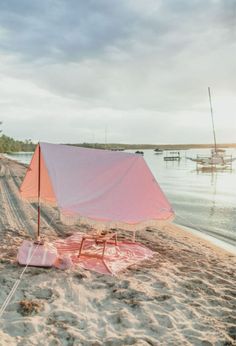 a pink tent sitting on top of a sandy beach