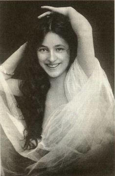 an old black and white photo of a woman with long hair wearing a sheer dress