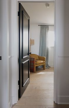 an open door leading to a living room with a couch and chair in the background