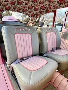 the interior of a car with pink and gray leather upholstered seats in front of floral wallpaper