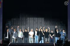 a group of people standing on top of a stage with their hands in the air