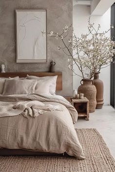 a large bed sitting next to two vases on top of a wooden table in a bedroom