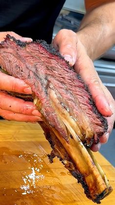 a person holding a piece of meat on top of a wooden table