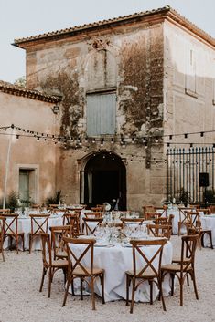 an old building with tables and chairs set up for a formal dinner in front of it