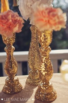 two gold vases with flowers in them on top of a table next to each other