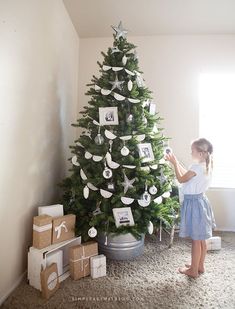 a decorated christmas tree in a living room with presents under it and pictures hanging from the top