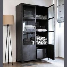 an open bookcase with folded towels and blankets on it in front of a lamp