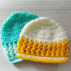 two crocheted hats sitting on top of a table