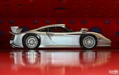 a silver sports car sitting on top of a red floor