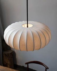 a white lamp hanging from a ceiling next to a wooden chair