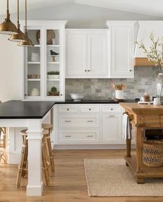 a kitchen with white cabinets and black counter tops, wooden stools and an island in the middle