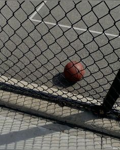 a basketball sitting on the ground behind a fence