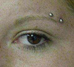 a woman with piercings on her eyes looks at the camera