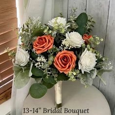 a bridal bouquet with orange and white flowers on a chair in front of a window