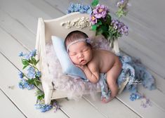 a newborn baby is sleeping in a white chair with blue flowers on the side and it's head resting on its pillow