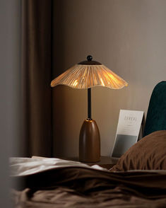 a lamp on a bedside table next to a bed with a brown comforter and pillows