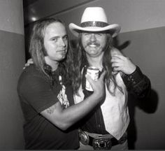 two men standing next to each other wearing cowboy hats