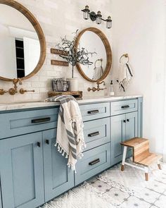 a bathroom with two round mirrors and blue cabinets