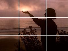 a person is standing on the beach with their hand out to the sun in front of them