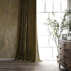 a room with a dresser, window and curtains