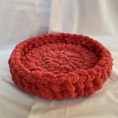 a red bowl sitting on top of a white sheet